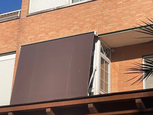 Toldo exterior enrollable instalado en fachada de ladrillo para protección solar de ventana