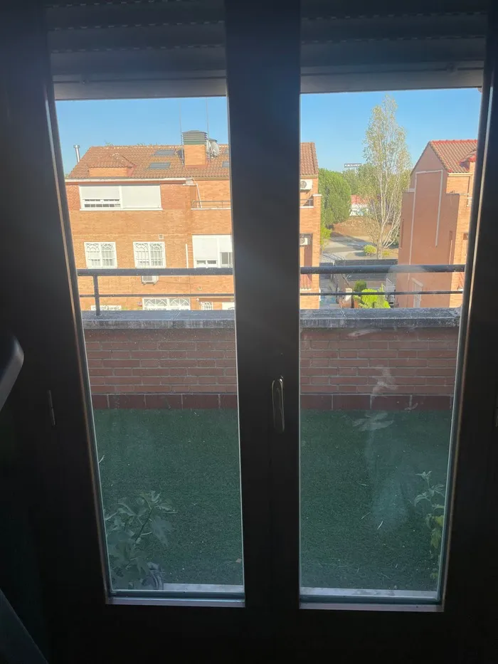 Puerta balconera de aluminio oscura con vistas a terraza exterior y edificios