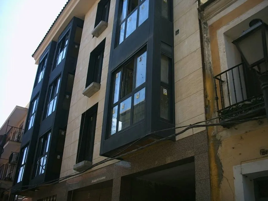 Fachada moderna de edificio residencial con ventanales oscuros y balcones