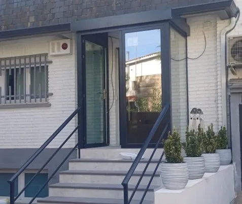 Cerramiento de entrada y puerta de aluminio con escaleras exteriores y fachada de ladrillo