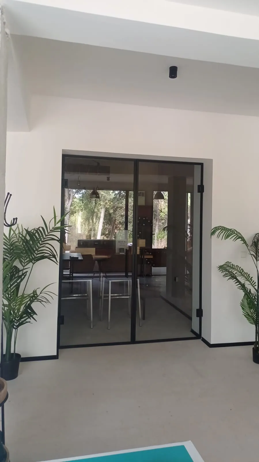 Puerta de aluminio acristalada en interior con vistas a comedor y plantas decorativas