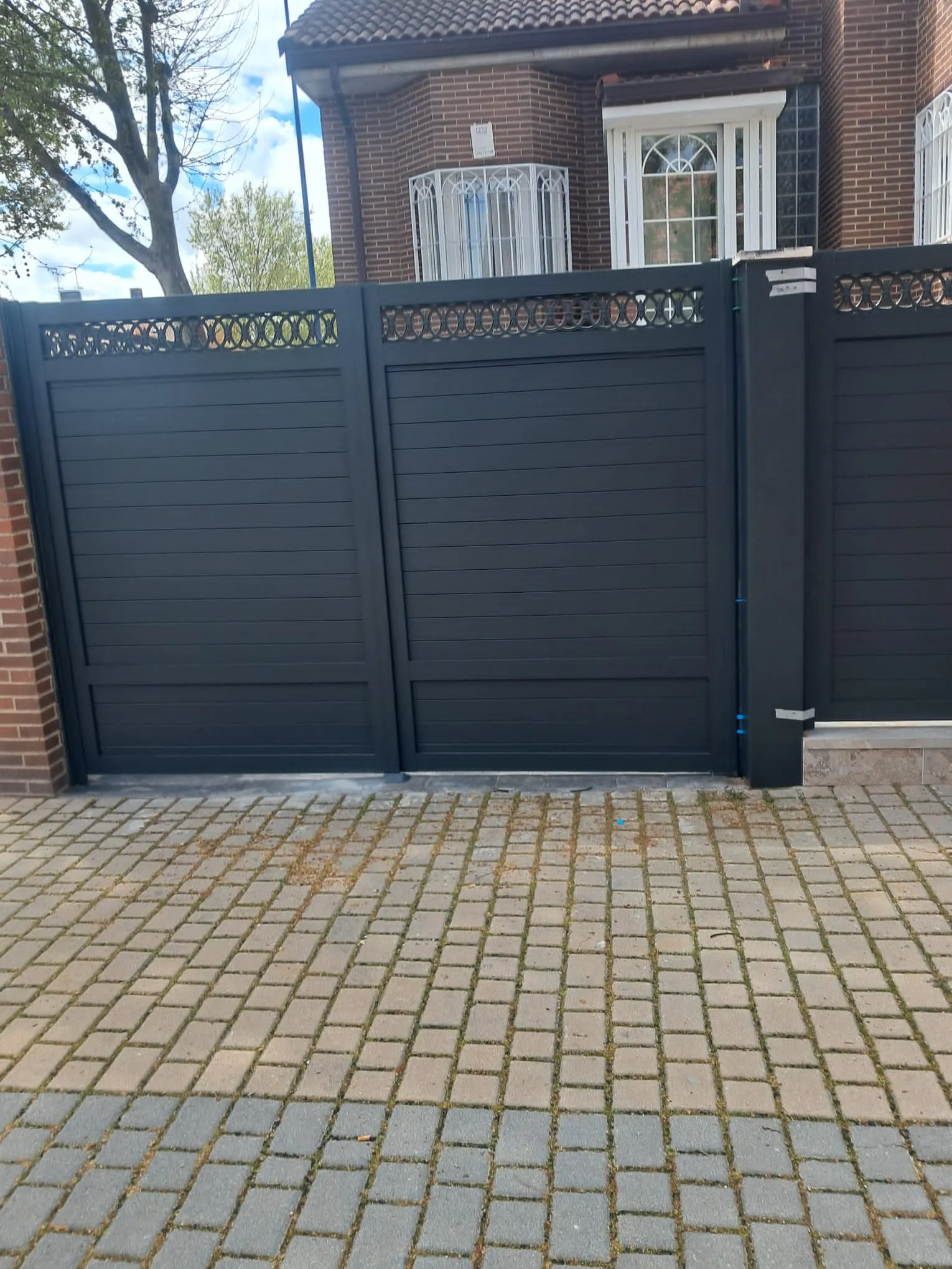 Puerta exterior de entrada de aluminio en tono oscuro para zona residencial