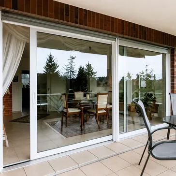 Gran puerta corredera de aluminio blanca con vistas a salón comedor y porche